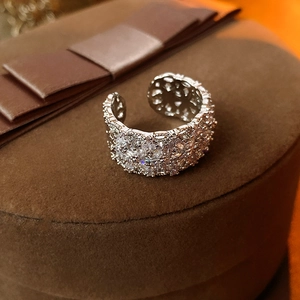 Gros plan d'une bague large argentée pavée de zircons sur un écrin en velours marron