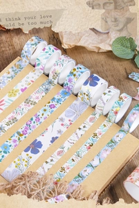 Close-up of floral washi tapes with gold foil on a vintage notebook with wooden background