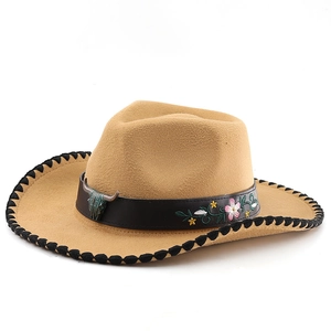 Detail of khaki cowboy hat featuring embroidered floral leather band and bronze bull head buckle