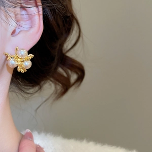 Detail view of French vintage gold floral stud earrings with round pearls on ear