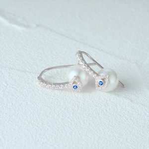 Detailed close-up of S925 sterling silver stamp on blue evil eye pearl earrings