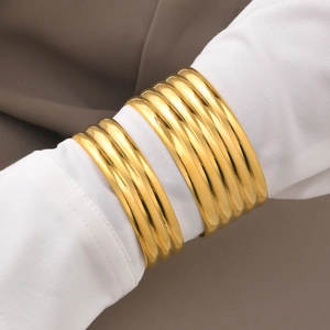 Close-up of stacked gold multi-layer bangles over a white shirt sleeve for a stylish look