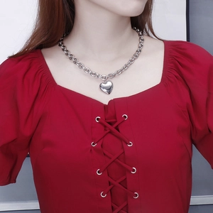 Polished silver heart pendant necklace on thick chain styled with a red square-neck top