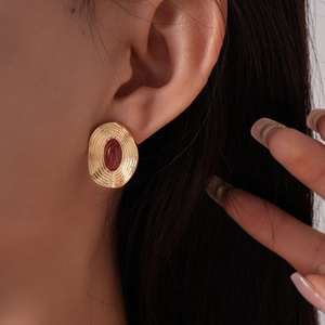 Gros plan d'une boucle d'oreille vintage dorée avec une gemme ovale rouge sur l'oreille