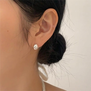 Close-up of model wearing irregular silver lava stud earrings with a glossy mirror finish