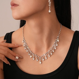 Macro detail of luxury silver jewelry set with teardrop crystals worn by a model