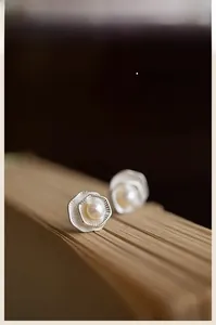 Detail macro shot of double-layered lotus pearl earrings on vintage paper background