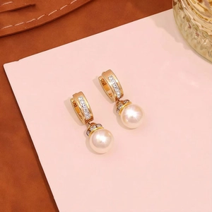 Detailed view of elegant gold U-shaped earrings with micro-inlaid diamonds and white pearls