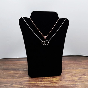 L-shaped black velvet bust stand displaying silver and rose gold interlocking necklaces