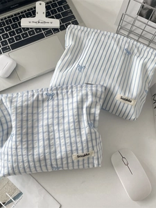 Trousse à maquillage en coton à carreaux et rayures bleues avec broderie sur un bureau