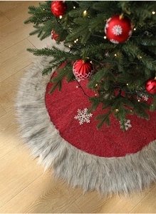 Detail of red Christmas tree skirt with white snowflakes and grey faux fur plush border