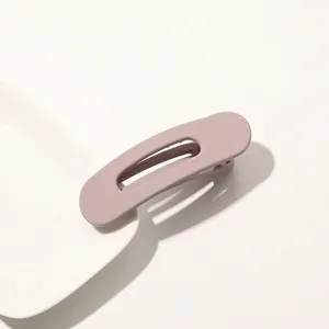 Detail of matte dusty rose hair clip on white ceramic plate with soft shadows