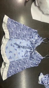 Detailansicht eines blauen Camisole-Kleids mit Blumenmuster, Rüschensaum und Schnürung vorne