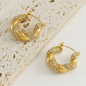 Detail of twisted 18k gold stainless steel earrings with sparkling crystal pavé
