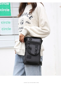 Detail of a black nylon tactical waist bag with multi-zipper pockets and metal D-ring