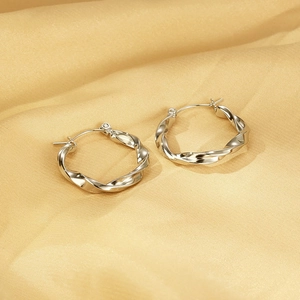 Gros plan détaillé de boucles d'oreilles torsadées en argent sur tissu de soie dorée