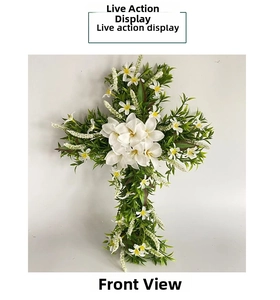 Detail showing artificial white lilies and green leaves on a cross-shaped wreath