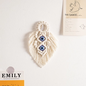 Detail of woven boho wall hanging with beige cotton ropes and blue evil eye beads