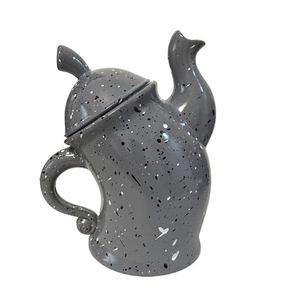 Detail of grey distorted ceramic canister with black and white artistic paint splashes