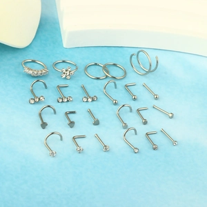 Detail of 20pc silver stainless steel nose rings set with crystal studs on blue background