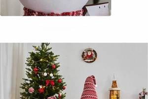 Détail d'un sapin de Noël illuminé avec un gnome rayé et une maison en bois lumineuse