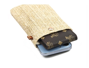 Detail view of woven straw phone bag with gold snap button and interior storage space