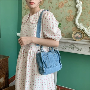 Close-up of vintage blue denim tote bag with adjustable shoulder strap on floral dress