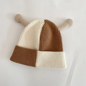 Détail du bonnet en maille à damier avec textures douces et cornes décoratives uniques