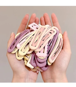 Close-up of pastel macaron-colored metal BB hair clips being held by hand