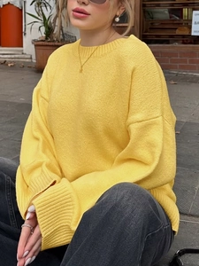 Detail eines gelben, lockeren Strickpullovers mit Rundhalsausschnitt und langen Ärmeln