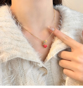 Close-up of 18k gold plated lucky bag necklace with red heart pendant worn on sweater