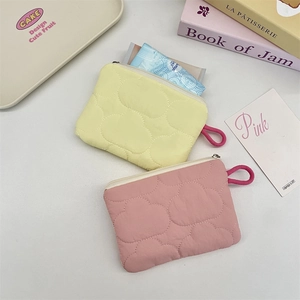 Detailed close-up of quilted yellow and pink coin pouches with secure white zipper
