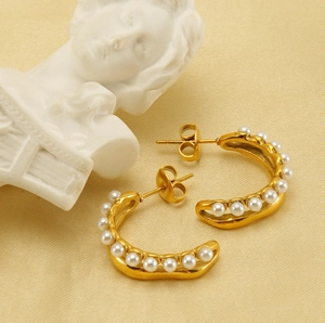 Detailed view of 18K gold-plated C-shaped earrings with elegant white pearl inlay