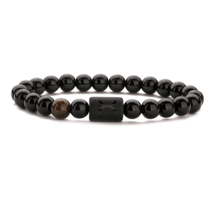 Macro shot of Taurus obsidian bead bracelet featuring a brown tiger eye stone detail