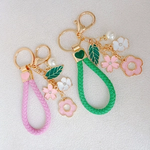 Floral keychain with pink and green woven rope charms featuring leaves and pearls