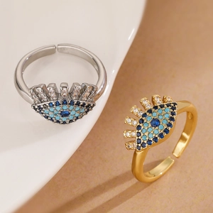 Gold and silver evil eye open rings with blue and white zircons on a white plate