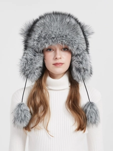 Detailed texture of grey faux fur trapper hat with fluffy ear flaps and hanging pom-poms