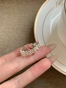 Close-up of minimalist silver daisy floral open ring worn with elegant background