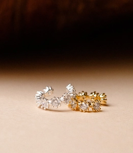Macro detail of gold and silver C-shaped ear cuffs with micro-paved white zircons