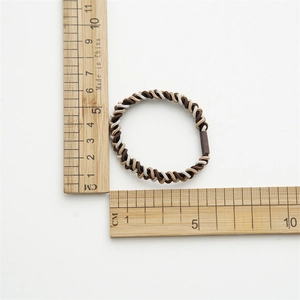 Close-up of a 5cm braided elastic hair tie being measured with a metric scale ruler