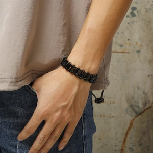 Detail of a matte black stainless steel motorcycle chain bracelet worn on a male wrist