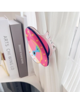 Detail showing cartoon UFO acrylic hair claw clip holding sheer white curtains in a home