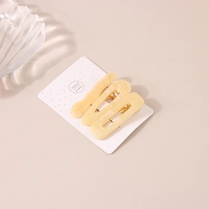 Lot de trois barrettes à cheveux effet marbre jaune en résine et métal doré sur carte