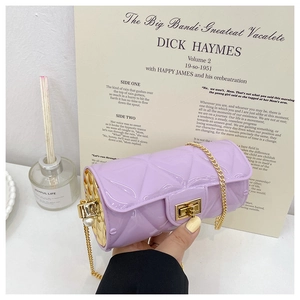 Detail of purple quilted cylinder bag with pearl accents and golden chain strap