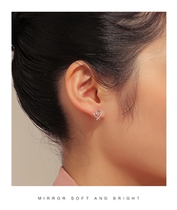 Close-up of heart-shaped silver earrings worn by a model in a minimalist style