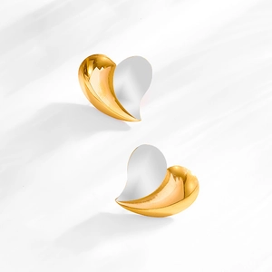 Detail of two-tone heart stud earrings in gold and silver finish with elegant shadows
