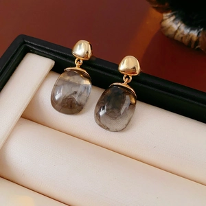 Detail view of 18K gold plated resin earrings with smoke texture in a jewelry box