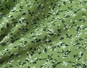 Vue détaillée du tissu en mousseline à fleurs vertes avec motifs blancs et noirs