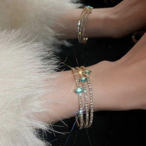 Detailed view of multilayer gold bracelet featuring blue marquise gemstones on a model
