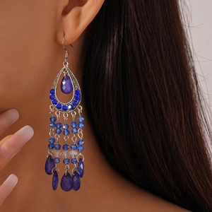 Close-up of bohemian blue crystal fringe earrings on model featuring teardrop hollow design